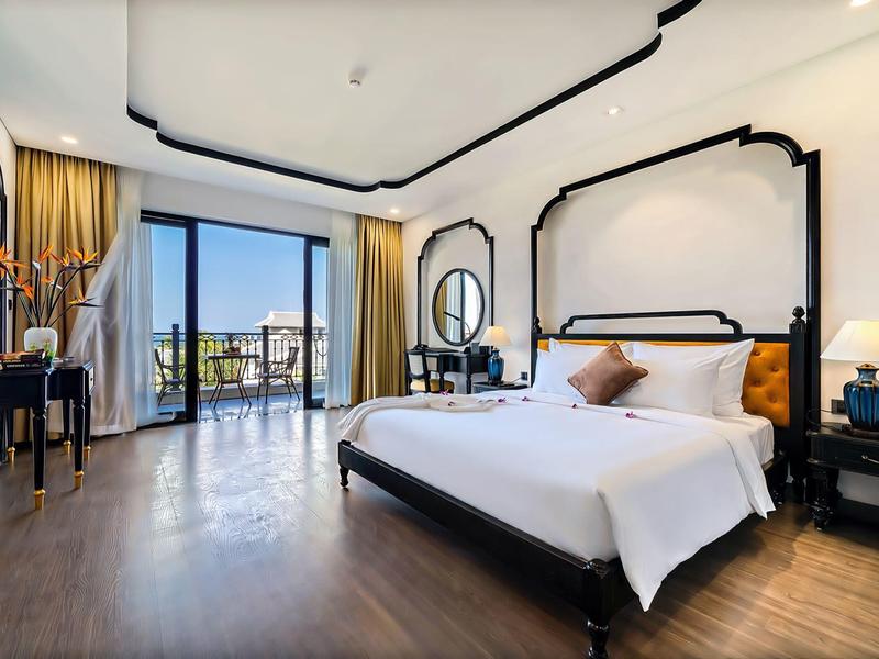 Lichte hotelkamer met groot bed, balkon en moderne inrichting met houten vloer.