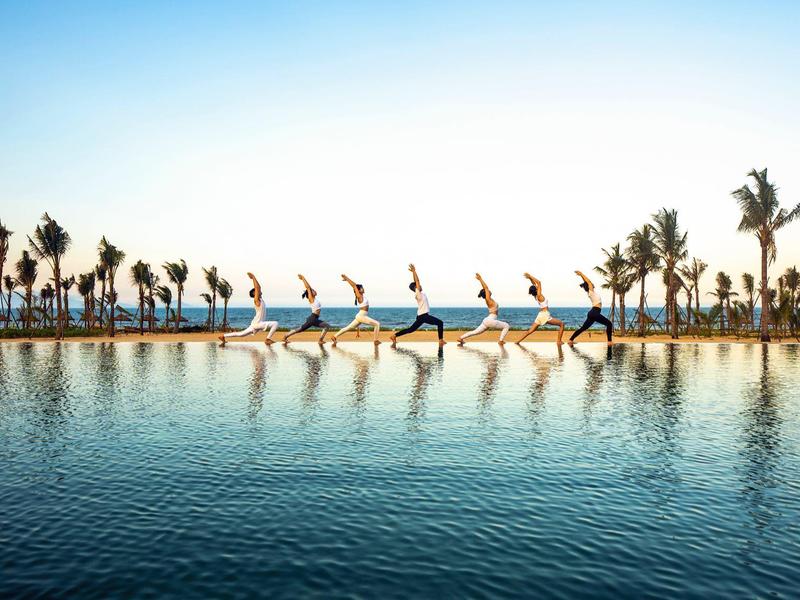 Een lang zwembad met palmbomen en meerdere synchroon uitgevoerde sprongen van een persoon aan de rand.