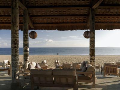 Überdachte Lounge mit Sitzmöbeln am Strand mit Blick auf das Meer und den Horizont.