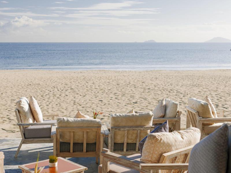 Strandterras met comfortabele zitplaatsen en uitzicht op zee onder bewolkte lucht.