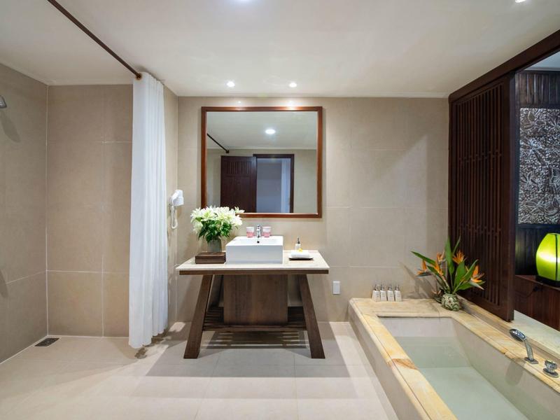 Modern badkamer met bad, douche, grote spiegel en houten meubels.