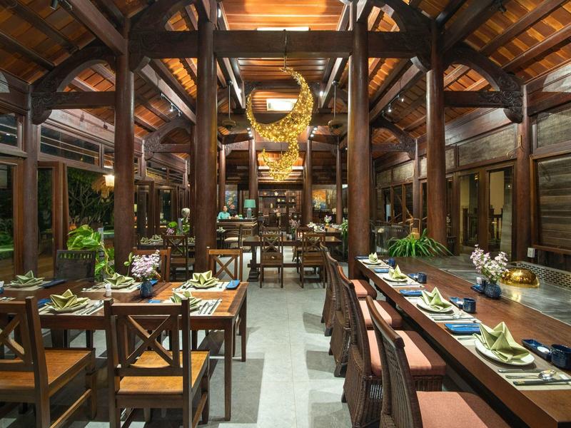 Elegant restaurant met houten meubels, gedekte tafels en warm licht.