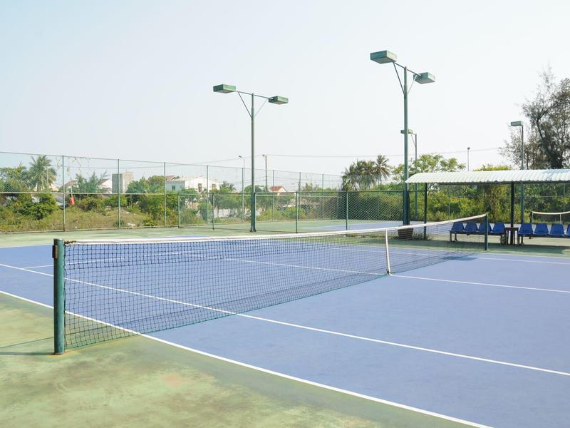Blauw buitentennisveld met net en groene randen bij daglicht