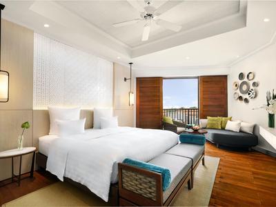 Camera d'albergo moderna con letto grande, zona salotto e vista sul mare.