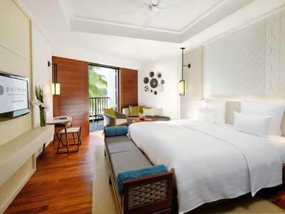 Camera d'hotel moderna con due letti, pavimento in legno e grande finestra con vista sul verde.