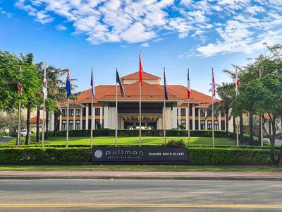 Edificio con tetti rossi circondato da alberi e bandiere sotto un cielo sereno