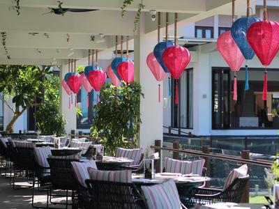 Terrazza esterna con tavoli da pranzo e lanterne rosse, circondata da architettura moderna e alberi.