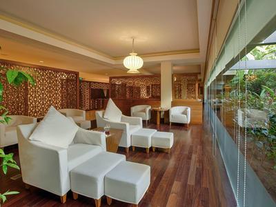 Lounge di hotel moderna con poltrone bianche, pavimento in legno e grande finestra sul giardino.
