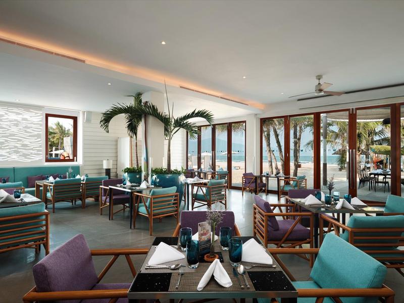 Area lounge moderna dell'hotel con sedute blu e grandi finestre con vista mare