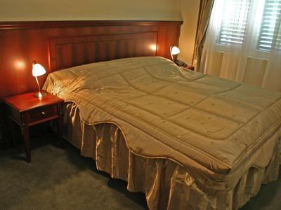 Gemütliches Schlafzimmer mit großem Doppelbett, Holzkopfteil, Nachttisch und sanfter Beleuchtung.