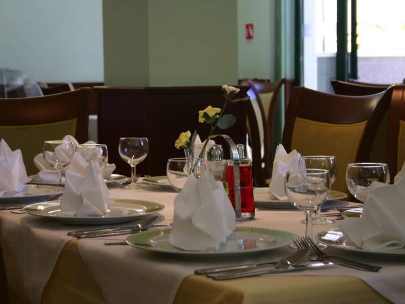 Eleganter gedeckter Tisch mit weißen Servietten, Weingläsern und Besteck in hellem Restaurant.