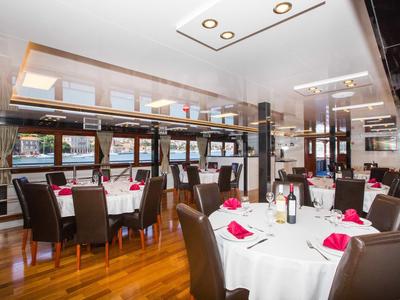 Elegantes Restaurant mit weißen Tischtüchern, roten Servietten und braunen Stühlen auf Holzboden.