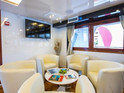 Cozy seating area with cream chairs, small table, and large TV in hotel room.