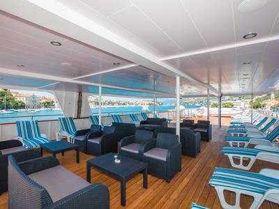 Covered terrace with seating groups and lounge chairs overlooking the water.