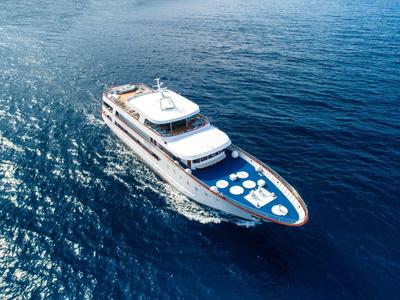 Luxury yacht cruising on calm, deep blue sea under clear sky.
