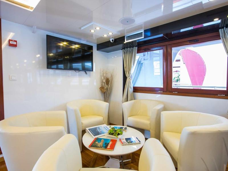 Cozy seating area with cream chairs, small table, and large TV in hotel room.