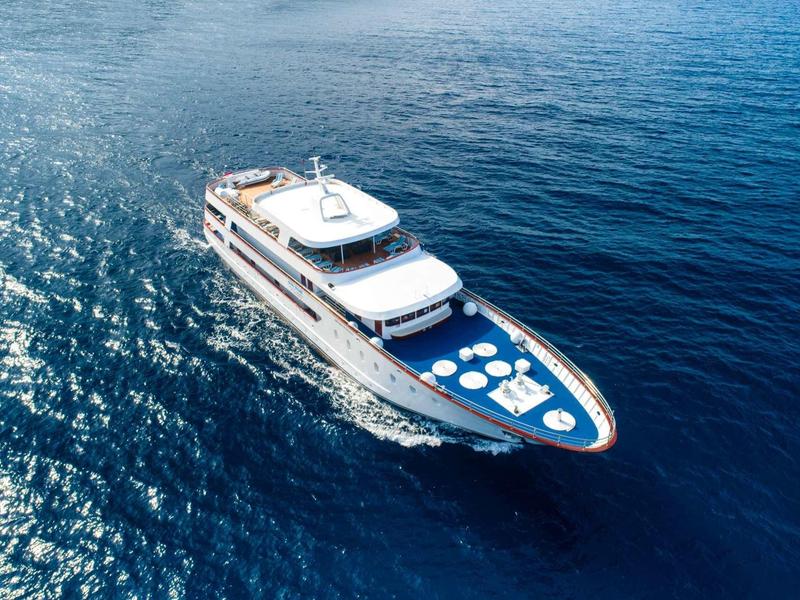 Luxury yacht cruising on calm, deep blue sea under clear sky.