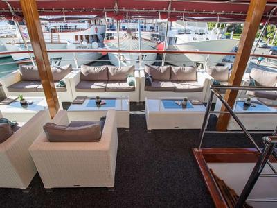 Moderne Lounge mit weißen Sofas und Tischchen, offene Holzstruktur, Blick auf hafen mit Booten.