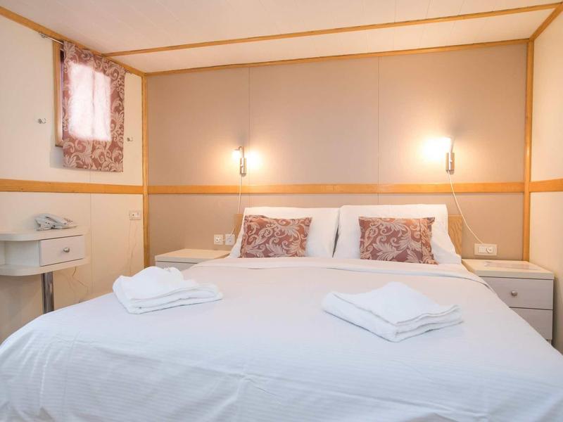 Gemütliches Schlafzimmer mit großem weißen Bett, weichen Kissen und sanfter Wandbeleuchtung.