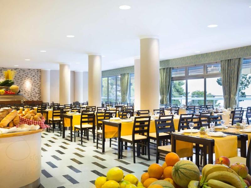 Bright, modern restaurant with set tables and a buffet of fresh fruit.