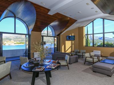 Nowoczesny salon z miejscami do siedzenia i dużymi oknami z widokiem na wodę.