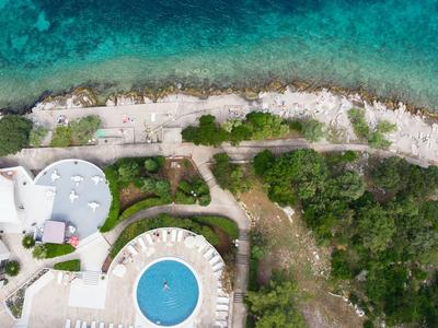 Widok z lotu ptaka na hotel z basenem obok skalistej linii brzegowej i turkusowego morza