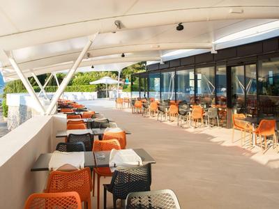 Duży taras z stołami i krzesłami, częściowo zadaszony z widokiem na góry.