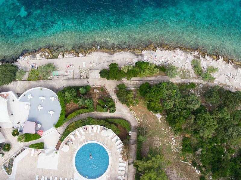 Widok z lotu ptaka na hotel z basenem obok skalistej linii brzegowej i turkusowego morza