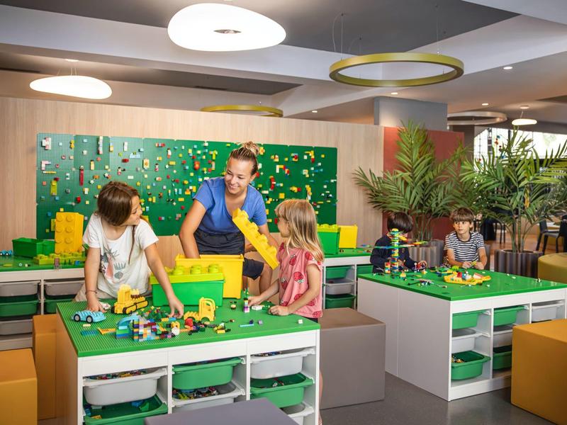Family playing together with colorful building blocks in a bright hotel playroom.