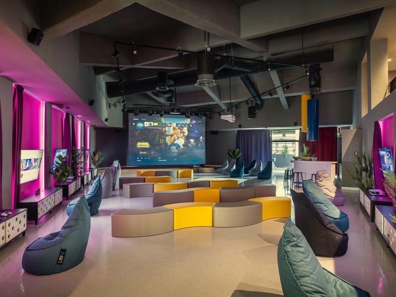 Modern lounge interior with bean bags, sofas, and large screens in vibrant colors.