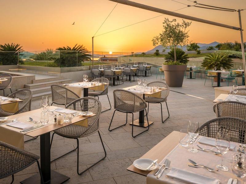 Terrace with set tables at sunset overlooking the landscape.