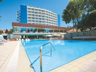 Modern hotel met groot buitenzwembad en zonneterras bij helder weer.