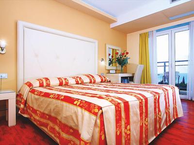 Gezellige hotelkamer met tweepersoonsbed, bureau en balkon met gordijnen.