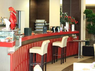 Moderne bar met hoge witte stoelen en rode balie in een hotelrestaurant.