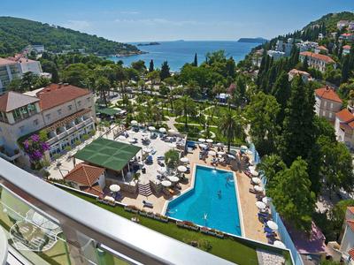 Blick auf ein Hotel mit Pool und Garten in Küstennähe und Meer im Hintergrund.