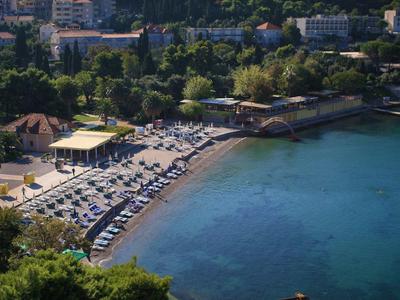 Overzicht van een strand met ligbedden, parasols en een strandbar langs de kust.