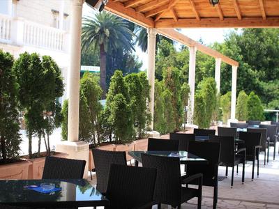 Buitenterras met zwarte stoelen en tafels onder een houten pergola.