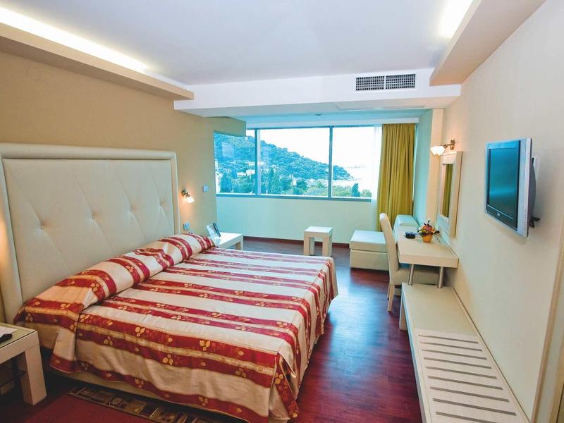 Gezellige hotelkamer met tweepersoonsbed, bureau en raam met uitzicht op de bergen.