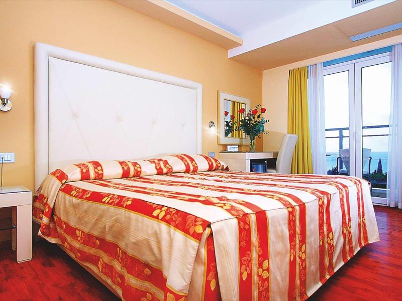 Gezellige hotelkamer met tweepersoonsbed, bureau en balkon met gordijnen.