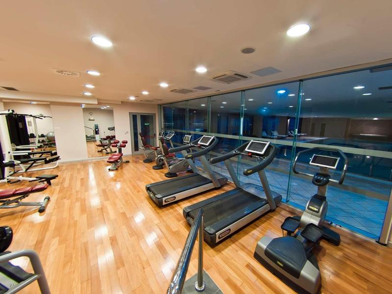 Modern fitnessruimte in hotel met loopbanden en cardiotoestellen naast grote ramen.