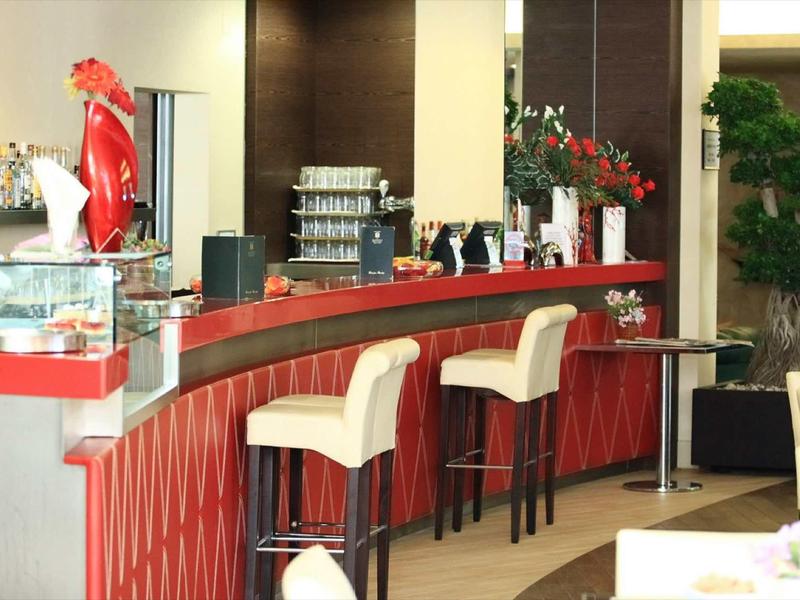 Moderne bar met hoge witte stoelen en rode balie in een hotelrestaurant.