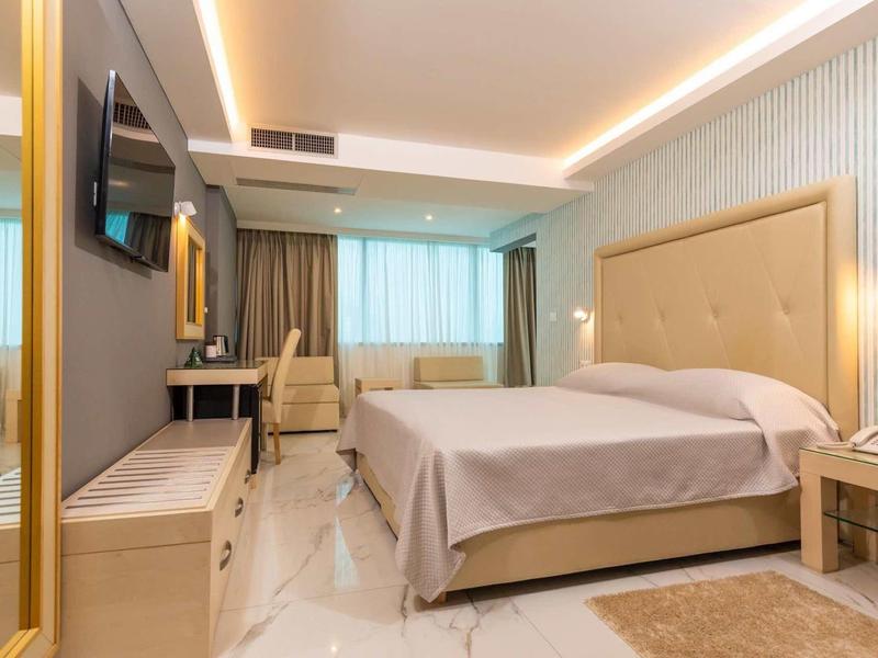 Moderne hotelkamer met groot bed, bureau, stoel en flatscreen-tv.