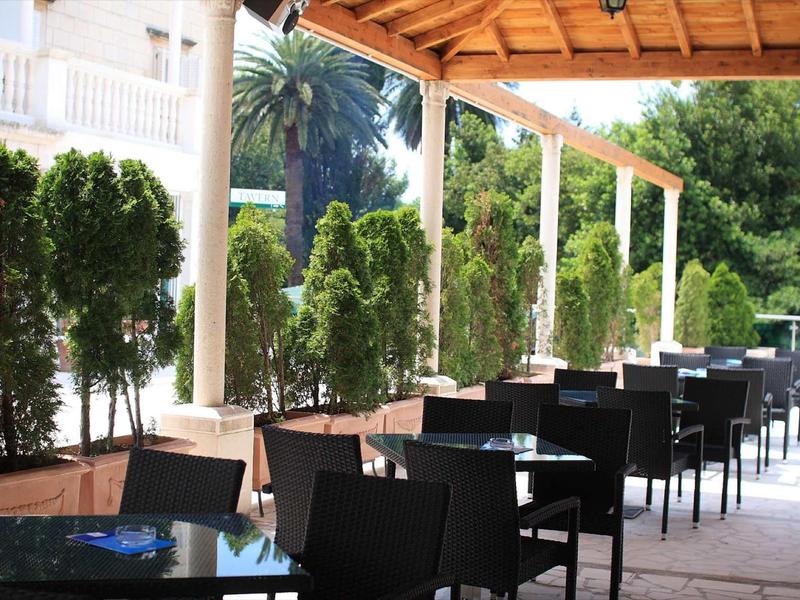 Buitenterras met zwarte stoelen en tafels onder een houten pergola.