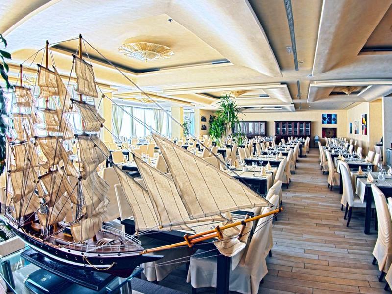 Restaurant met nautisch modelschip en licht houten meubels in een hotel.