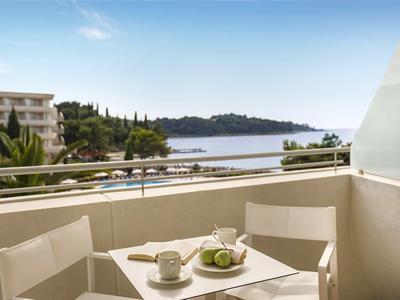 Balkon mit Tisch und Stühlen mit Blick auf das Meer und umliegende Gebäude.