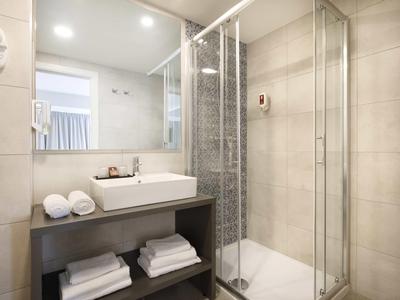 Helles, modernes Badezimmer mit Glas-Duschkabine, Waschbecken und Handtüchern.