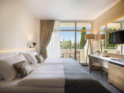 Modernes Hotelzimmer mit Doppelbett, großem Fenster und Terrasse mit Aussicht.