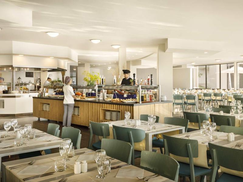 Heller, moderner Speisesaal mit gedeckten Tischen und mehreren Gästen am Buffetbereich.