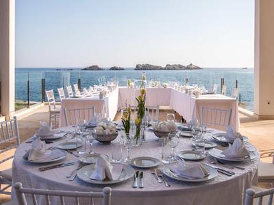 Eleganter runder Esstisch mit weißen Stühlen auf der Terrasse mit Meerblick.