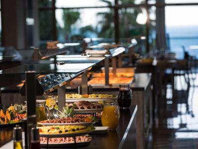 Hotel restaurant buffet with various dishes and sea view.